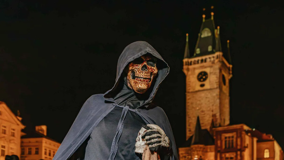 Ghost tour guide and group near Charles Bridge in the Old Town of Prague at night, Czechia